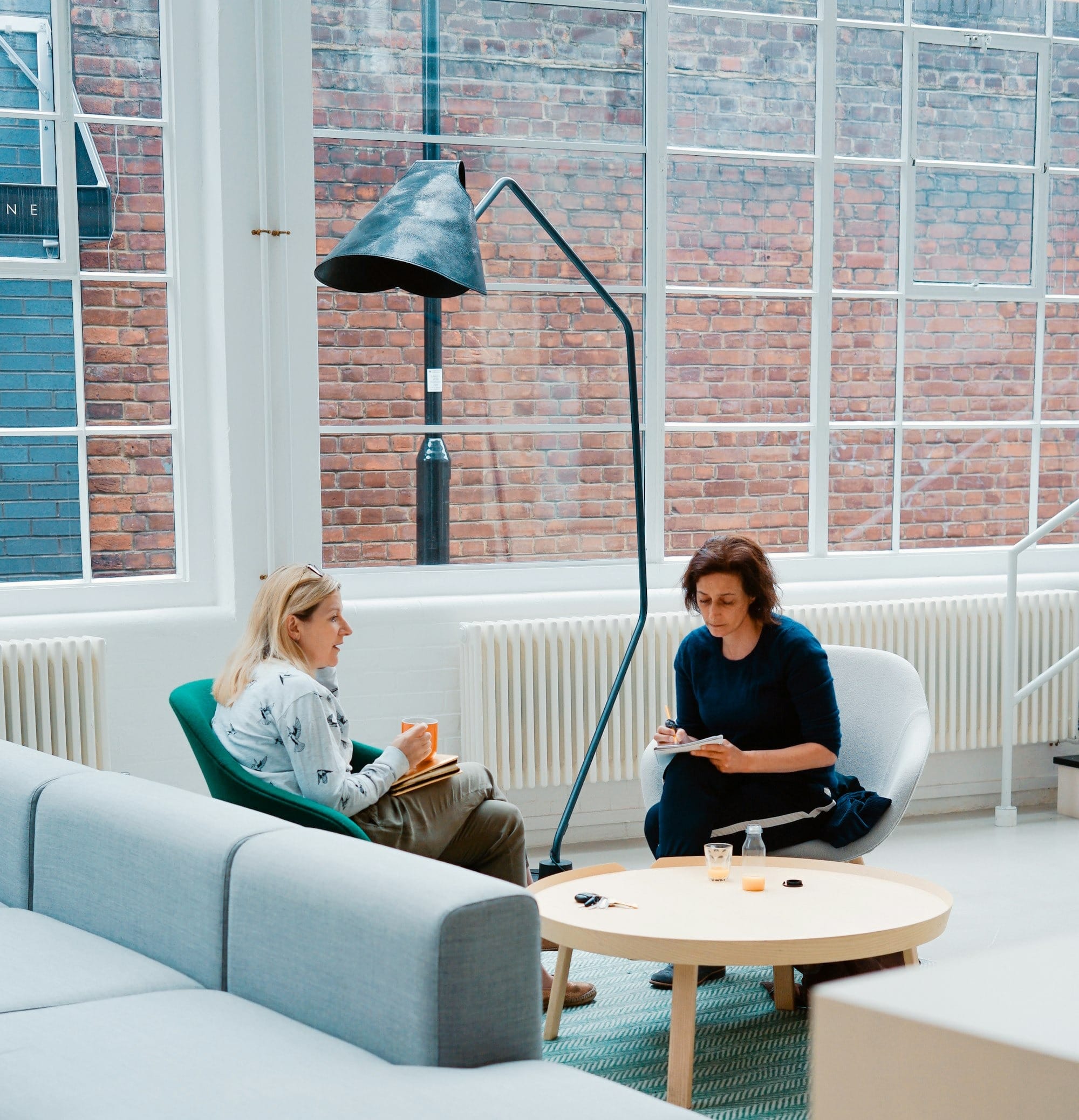 two woman sits on sofa chairs inside house